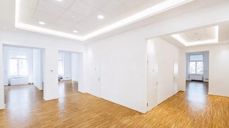 Geräumiger, heller Büroraum mit modernem Holzparkett und indirekter Deckenbeleuchtung, bereit zur Einrichtung.
