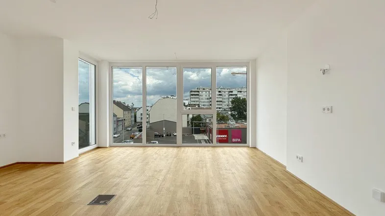 Heller Wohnraum mit großen Fenstern, Holzboden und Blick auf die Stadt.
