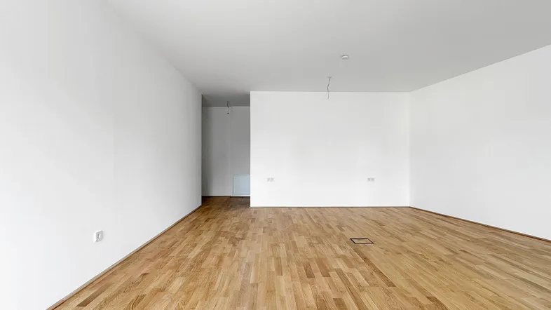 Heller, leerer Raum mit weißen Wänden und hellem Holzfußboden, bereit zur individuellen Gestaltung.