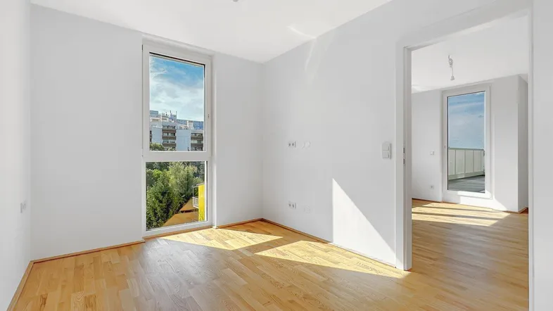 Helles Zimmer mit Parkettboden und Blick ins Grüne, ideal als Wohn- oder Schlafbereich.
