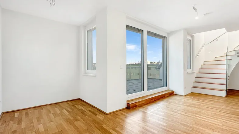 Helles Wohnzimmer mit Parkettboden, großen Fenstern und Zugang zu einer Terrasse.