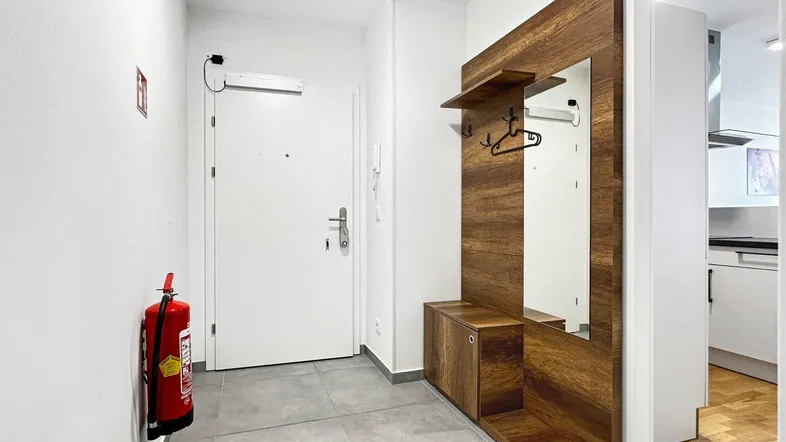 Heller Eingangsbereich mit moderner Garderobe aus Holz und Fliesenboden.