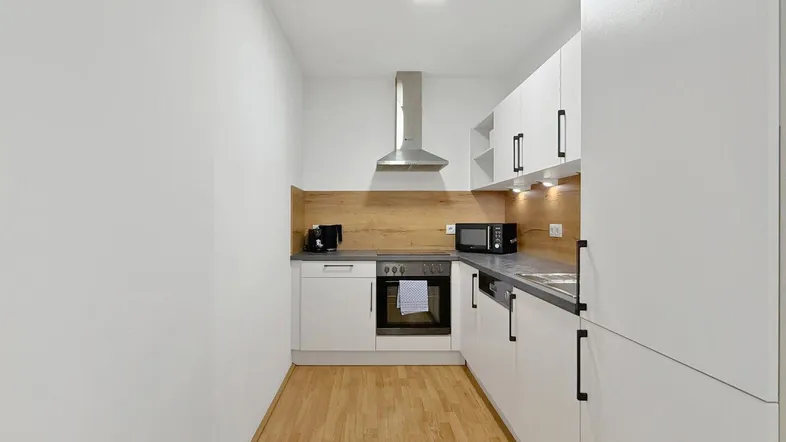 Moderne Küche mit weißen Schränken, Holzrückwand und integrierten Geräten.