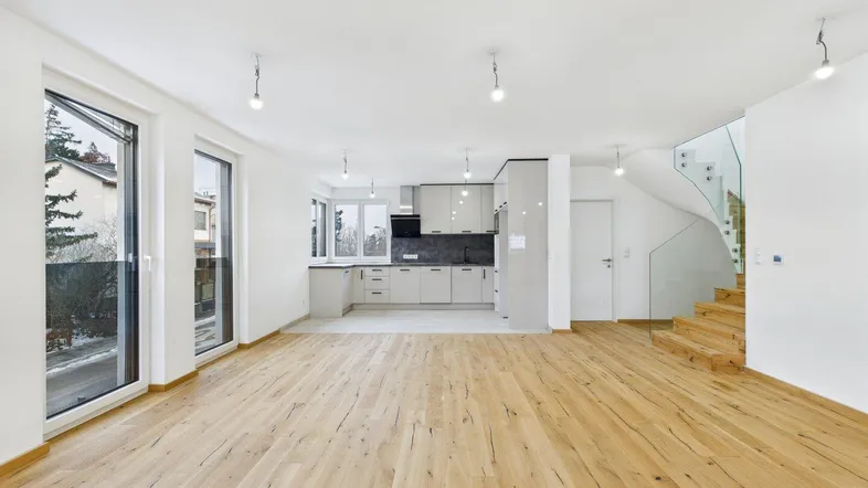 Geräumiger offener Wohnbereich mit moderner Küche, Holzboden und eleganter Glastreppe.