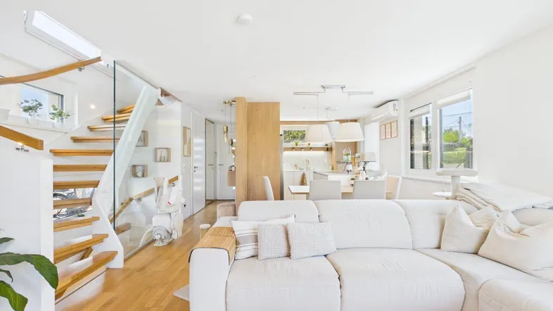 Helles, offenes Wohnzimmer mit Holzboden, bequemer Couch und Treppe zum Obergeschoss.