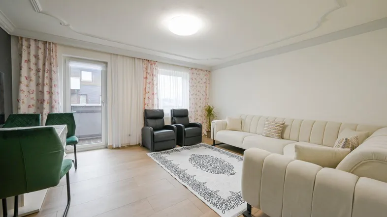 Helles Wohn- und Esszimmer mit Parkettboden, Stuckdecke und Zugang zum Balkon.
