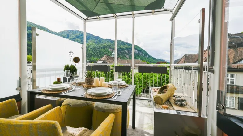 Gemütliche, verglaste Terrasse mit Esstisch und Stühlen, bietet einen malerischen Bergblick.