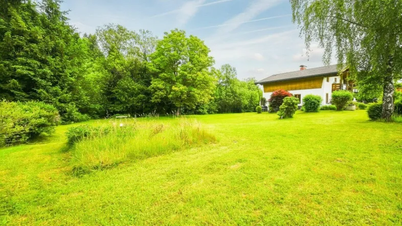 Großzügiger Gartenbereich mit weitläufiger Rasenfläche und Blick auf das charmante Landhaus.