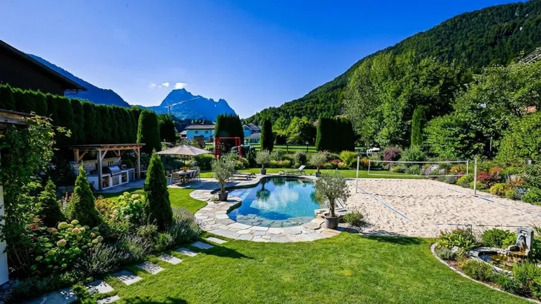Großer Garten mit Pool, Sand-Volleyballfeld, Außenküche und herrlichem Bergblick.