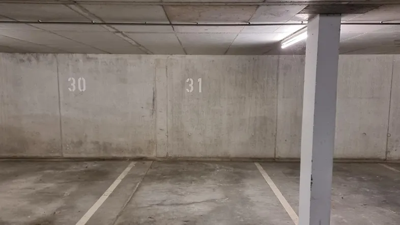 Tiefgarage mit Betonwänden, markierten Parkplätzen und einer tragenden Säule.