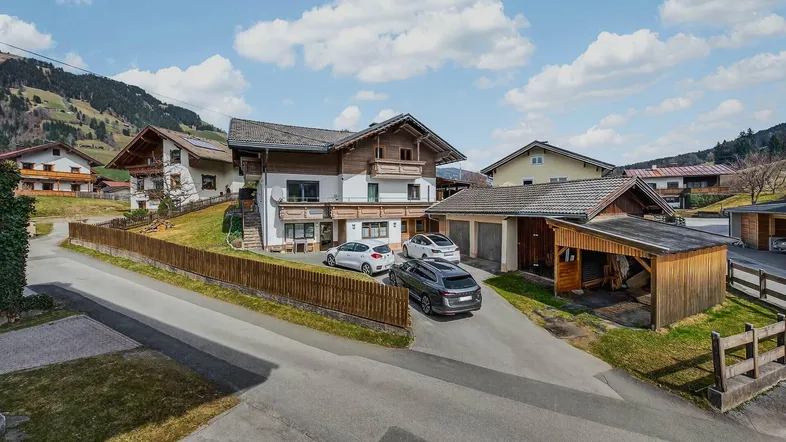 Traditionelles Wohnhaus im alpinen Stil mit Holzbalkonen und gepflegter Auffahrt in ländlicher Umgebung.
