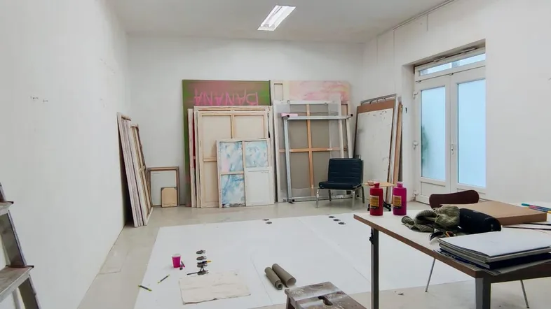 Geräumiges, helles Atelier mit hohen Decken, großen Fenstertüren und einem funktionalen Arbeitsbereich.
