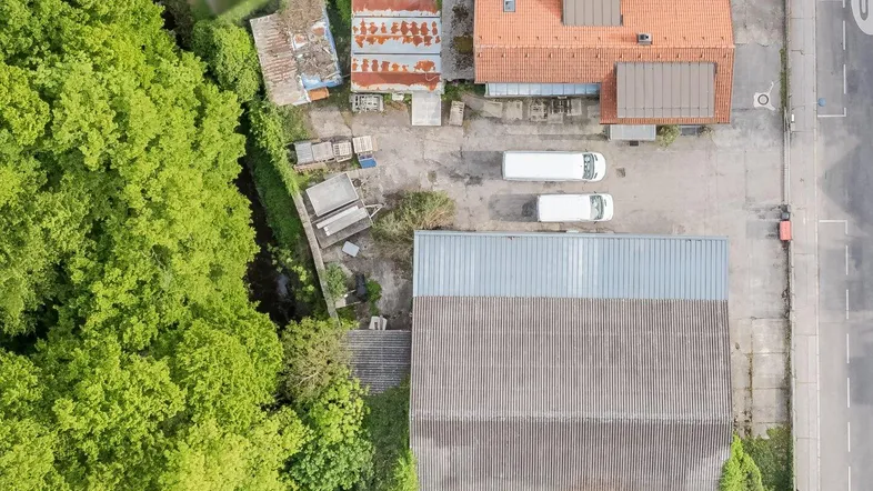 Luftaufnahme des Grundstücks mit Gebäuden und umliegender grüner Landschaft, die eine weite Sicht bietet.