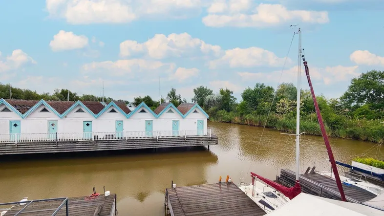 Blick auf die charmanten Häuser am Kanal mit Bootsanlegestellen unter einem bewölkten Himmel.