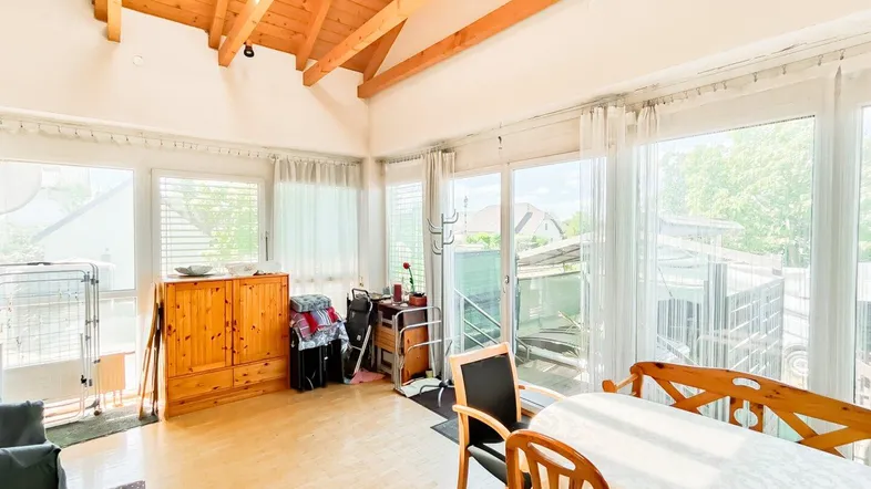 Heller Wohnbereich mit großen Fenstern, Holzboden und viel Tageslicht, ideal für Familienleben.