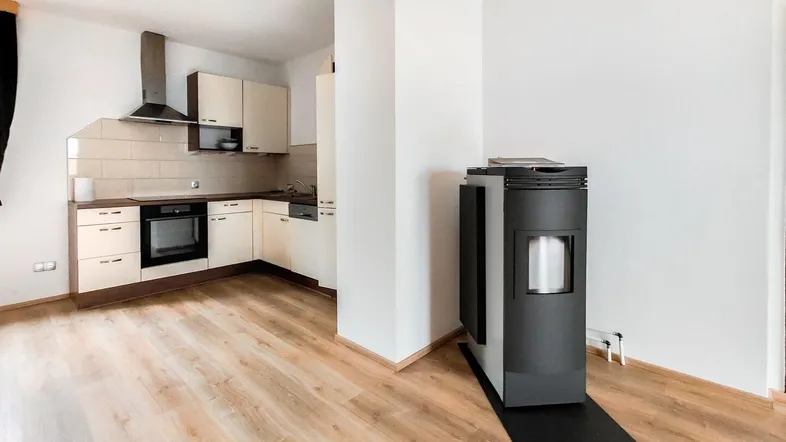 Offener Wohnbereich mit integrierter Küche, modernem Ofen und hellem Laminatboden.