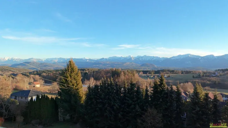 Weitläufiger Blick auf die umliegende Landschaft mit schneebedeckten Bergen am Horizont unter blauem Himmel.