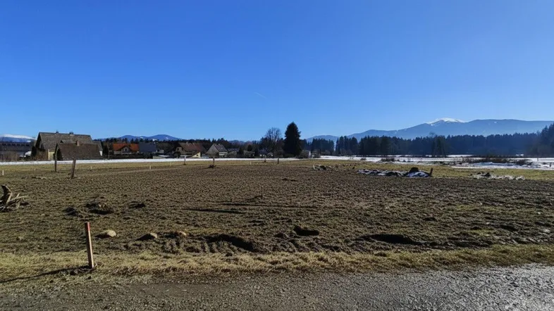 Weitläufiges Feld mit Blick auf die umliegende Landschaft und ferne Berge unter blauem Himmel.