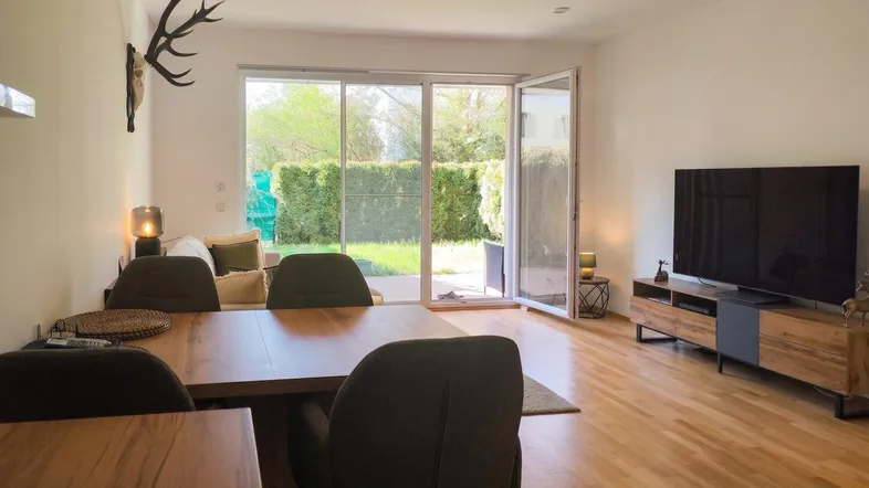 Helles Wohn- und Esszimmer mit Holzboden, Zugang zur Terrasse und Blick ins Grüne.
