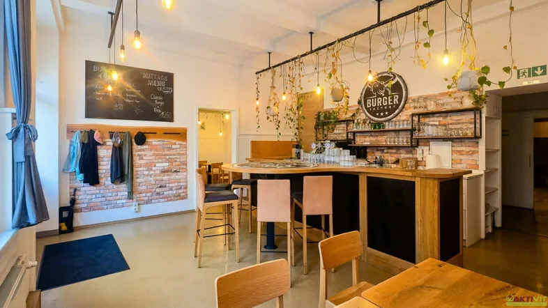Gemütlicher Restaurantbereich mit Bar, Backsteinwand, Holzboden und hängenden Pflanzen, ideal für Gäste.