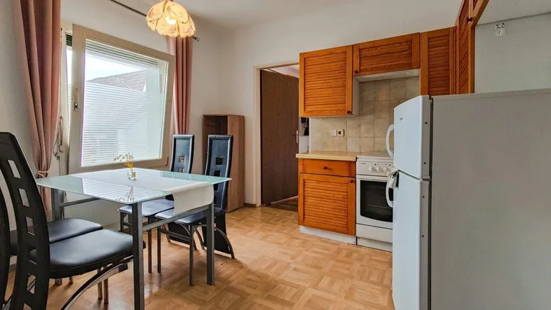 Helle Küche mit Essbereich, Holzschränken, Parkettboden und Blick nach draußen.