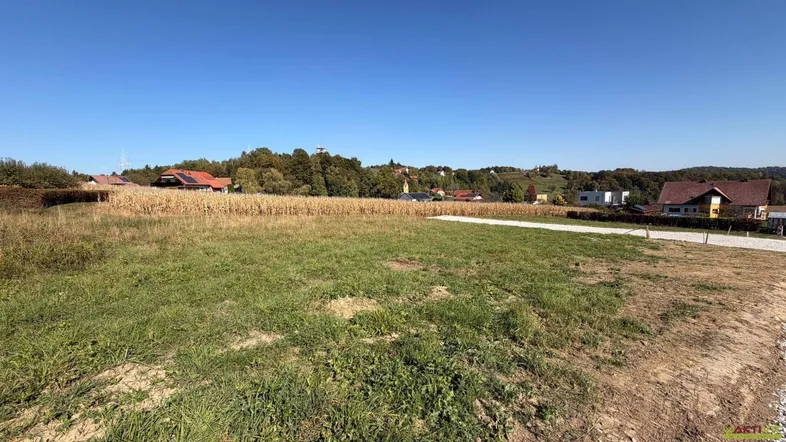 Weitläufiges Grundstück mit Grasfläche und Maisfeld im Hintergrund, umgeben von Häusern und Hügeln.
