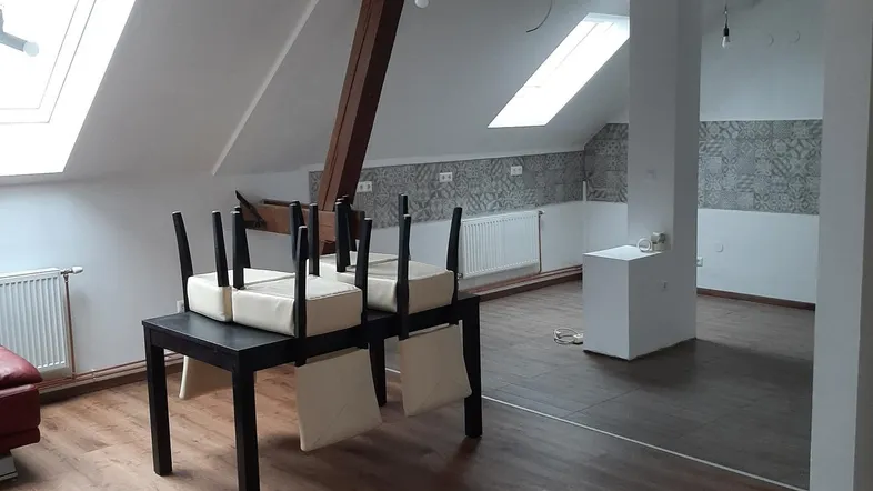 Geräumiger Dachbodenbereich mit Holzbalken, Laminatboden und mehreren Dachfenstern, der viel Potenzial bietet.