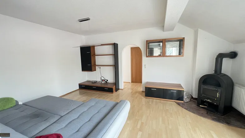 Helles Wohnzimmer mit Holzofen, Parkettboden und modernen Möbeln in neutralen Farben.