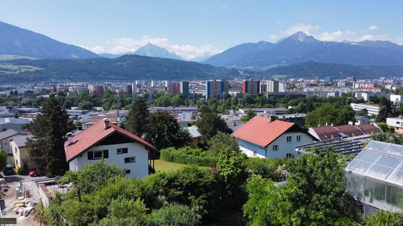 Panoramablick über die Stadt mit Wohngebäuden und majestätischen Bergen im Hintergrund.