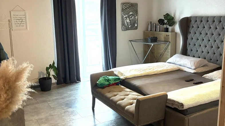 Gemütliches Schlafzimmer mit Holzbalkendecke, großem Bett und Zugang zum Balkon.