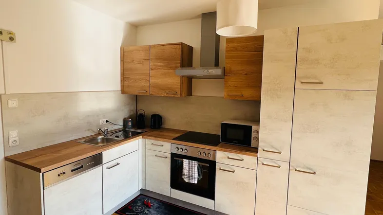 Moderne Küche mit hellen Holz- und Grautönen, ausgestattet mit Einbaugeräten und Parkettboden.