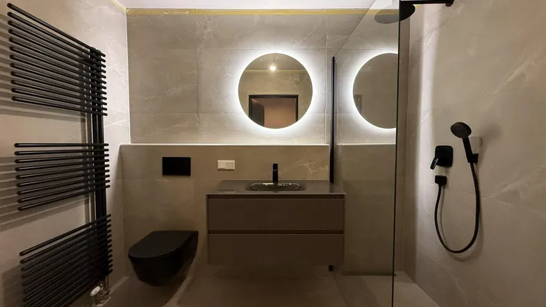 Modernes Badezimmer mit begehbarer Dusche, schwebendem Waschtisch und beheiztem Handtuchhalter in Grautönen.