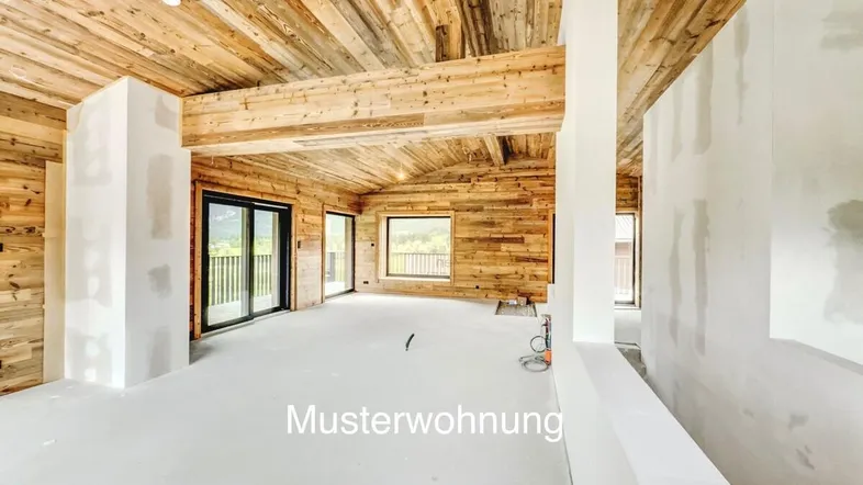 Unfertiger Innenraum mit Holzwänden und -decken, großen Fenstern und Bergblick.