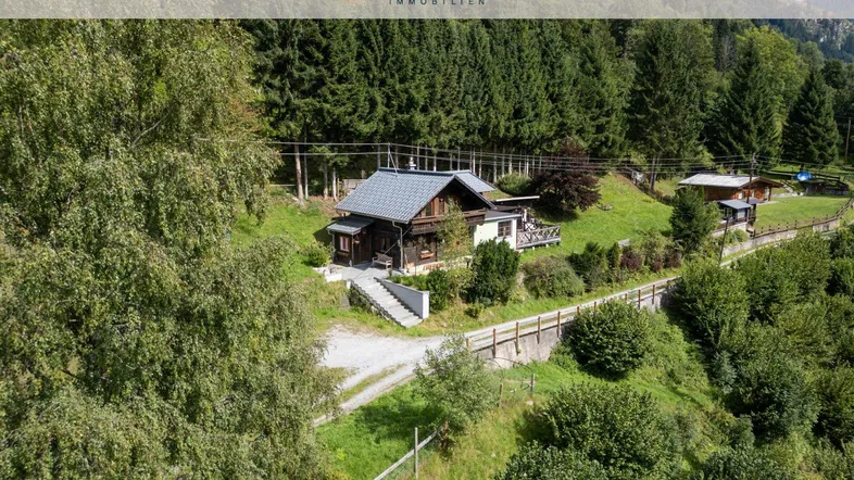 Charmantes Chalet in idyllischer alpiner Umgebung, umgeben von Wald und grünen Wiesen.