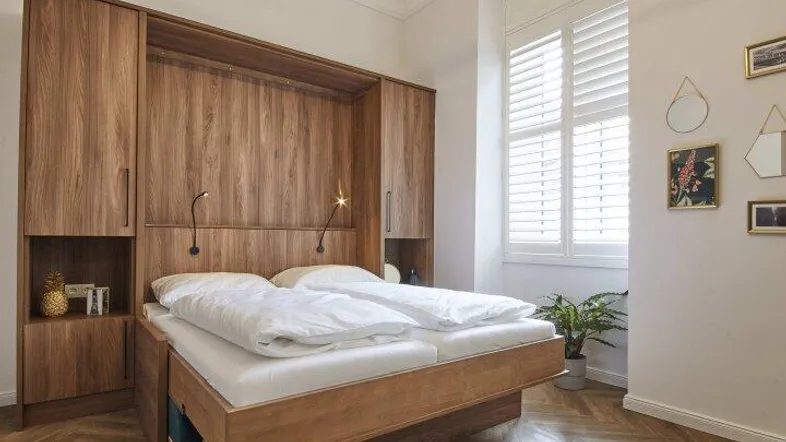 Gemütliches Schlafzimmer mit Holzbett, integrierten Schränken und elegantem Fischgrätparkettboden.