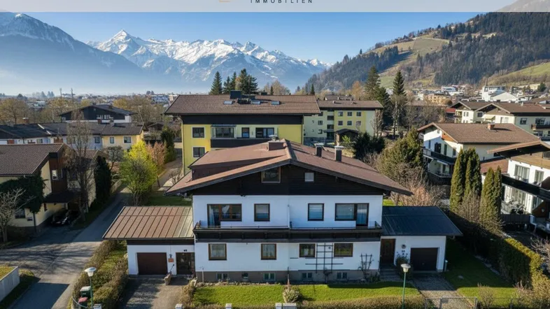 Luftaufnahme eines Wohnhauses mit Satteldach und beeindruckendem Bergblick im Hintergrund.