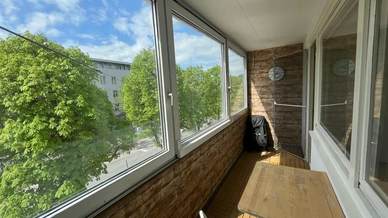 Geschlossene Loggia mit Sitzgelegenheiten und Blick ins Grüne, ideal zum Entspannen.