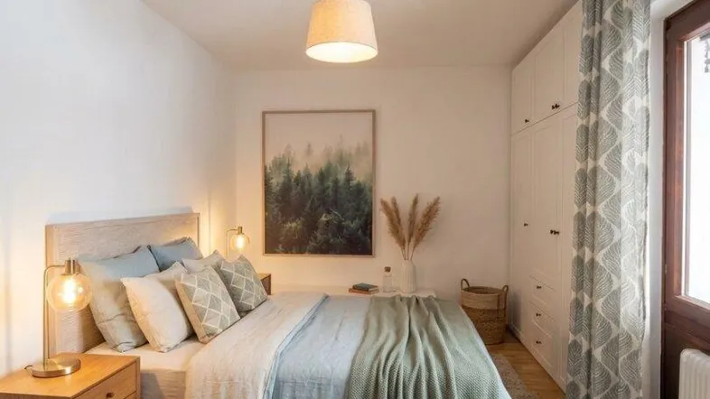 Helles Schlafzimmer mit Holzboden, gemütlichem Bett und integriertem Kleiderschrank.