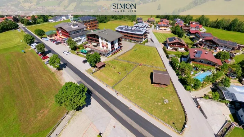Luftaufnahme eines Grundstücks mit mehreren Gebäuden, umgeben von grünen Wiesen und einer Straße.