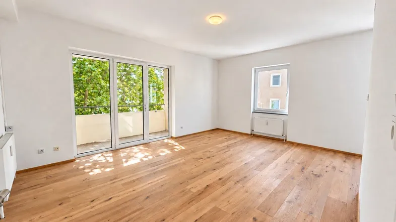 Helles Wohnzimmer mit neuem Eichenparkettboden und Zugang zu einem Balkon.