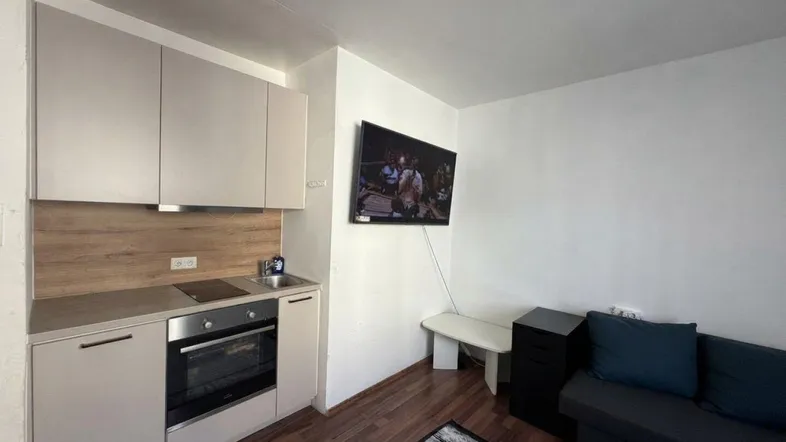 Kleine, funktionale Küchenzeile in einem kombinierten Wohnbereich mit Fernseher und Sofa.