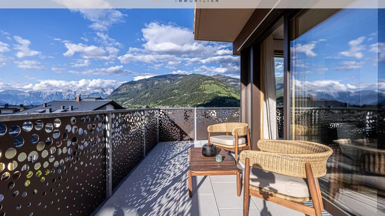 Geräumiger Balkon mit modernen Möbeln und atemberaubendem Bergblick unter blauem Himmel.