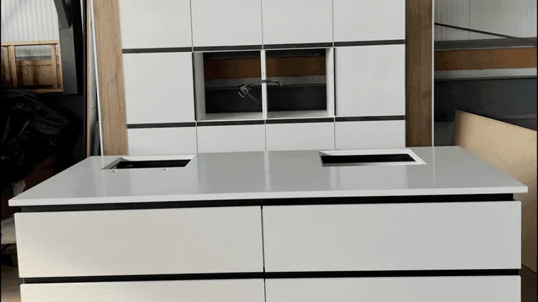 Moderne Küchenzeile mit weißen Fronten und integrierten Geräten, bereit zur Installation.