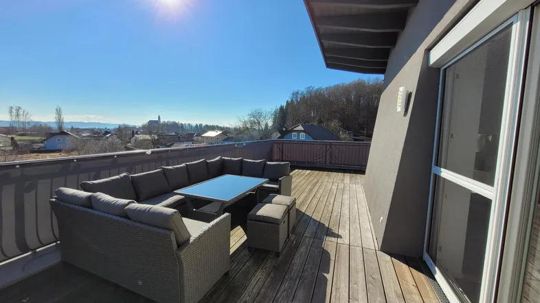 Sonnige Dachterrasse mit bequemen Gartenmöbeln und weitem Blick über die Landschaft.