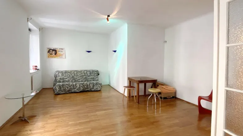Geräumiges Wohnzimmer mit hellem Parkettboden und minimalistischer Einrichtung, ideal für individuelle Gestaltung.