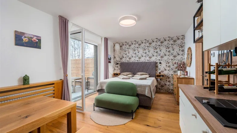 Helles Studio-Apartment mit Schlafbereich, Essplatz und integrierter Küchenzeile sowie Zugang zur Terrasse.