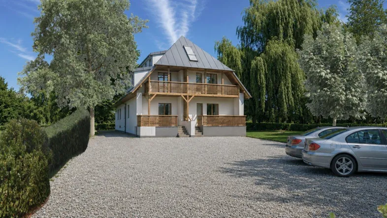 Modernes Haus mit markantem Dach, Balkonen und Kiesauffahrt, umgeben von Bäumen.