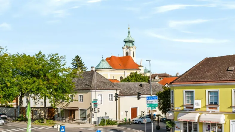 Blick auf die charmante Umgebung mit historischen Gebäuden und einer Kirche im Hintergrund.