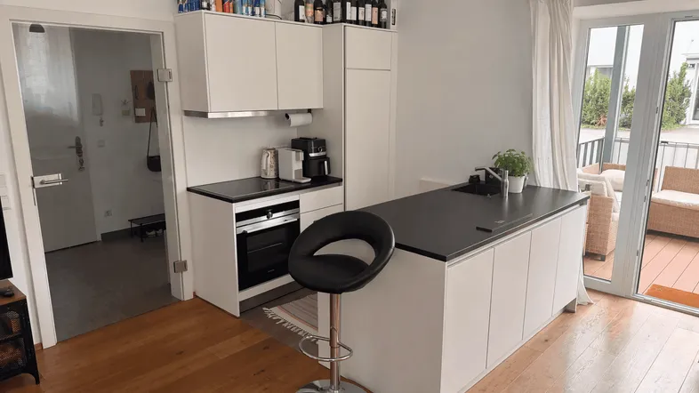 Moderne Küche mit Kochinsel, integrierten Geräten und Zugang zur Terrasse.