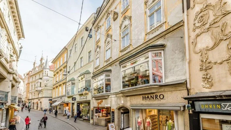 Historische Gebäude entlang einer belebten Einkaufsstraße mit traditioneller Architektur und Geschäften.
